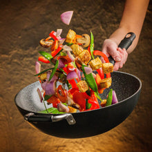 Hand tossing stir-fried vegetables and tofu in the DaTerra Cucina 13-inch nonstick wok