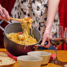 Serving pasta from the DaTerra Cucina 5-quart Dutch oven at a dinner table with wine and bread